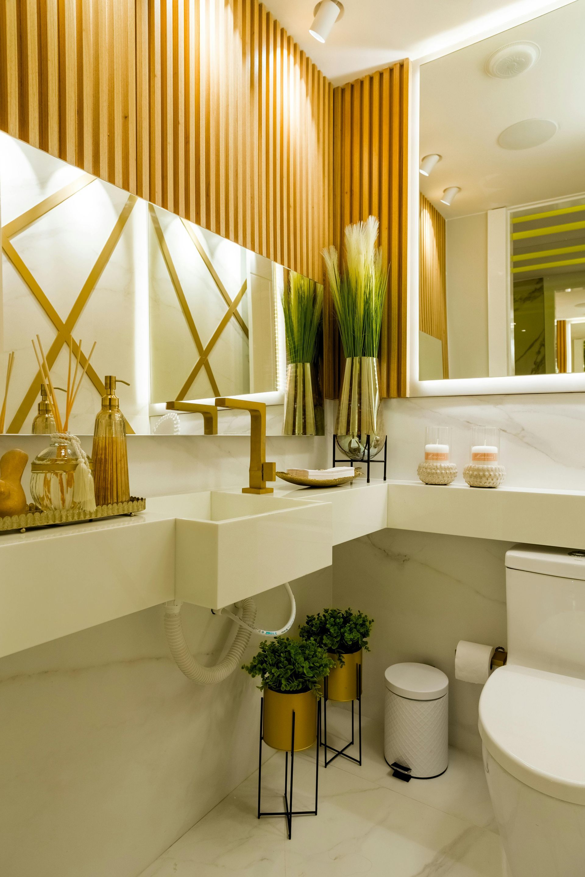 Modern bathroom with wood paneling, gold accents, floating sink, and potted plants.
