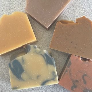 Handcrafted soap bars scattered on a neutral background, representing gentle daily cleansing.