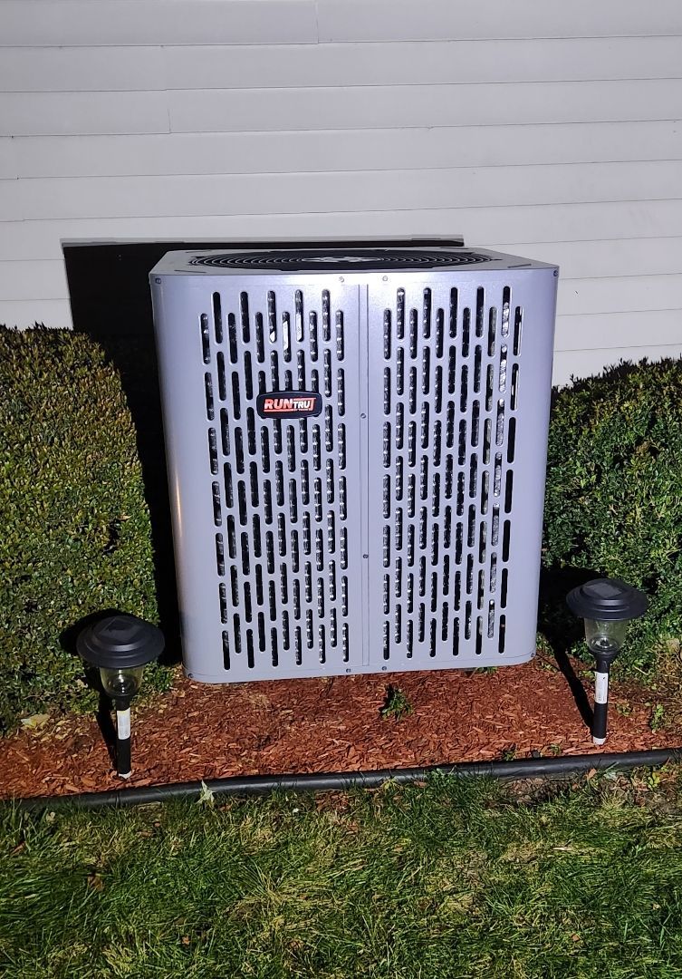 A large air conditioner is sitting on the side of a house.