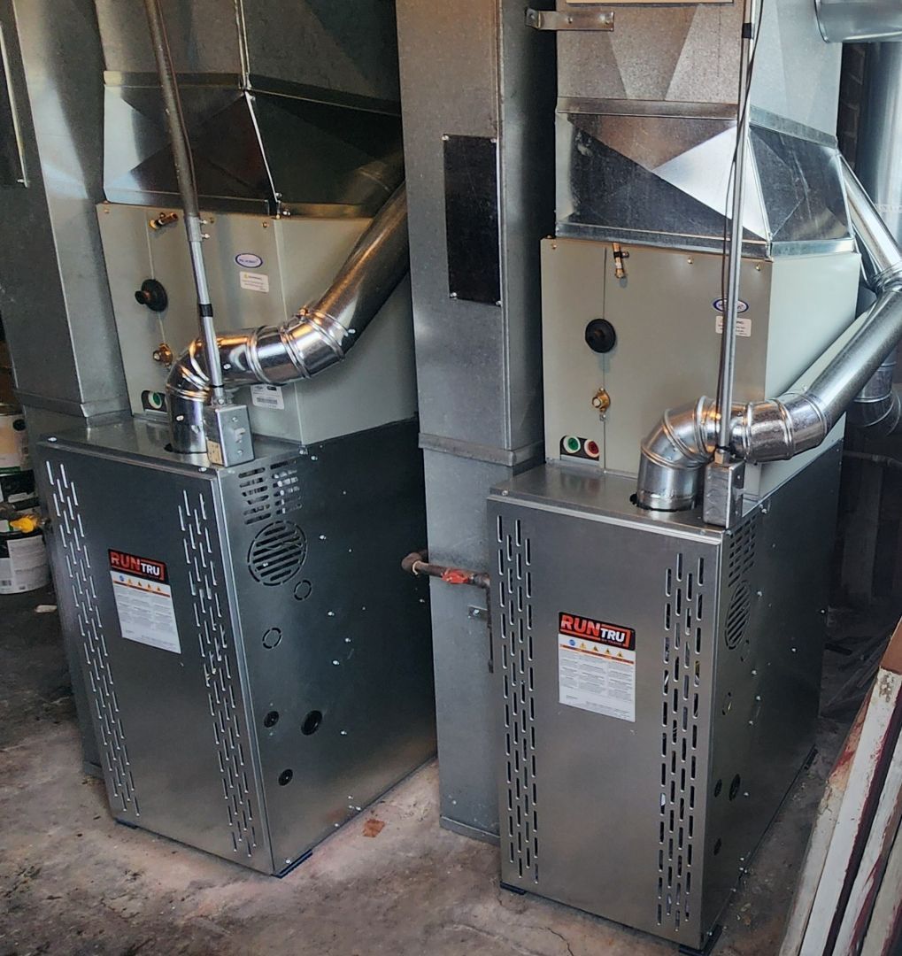 Two air conditioners are sitting next to each other in a garage