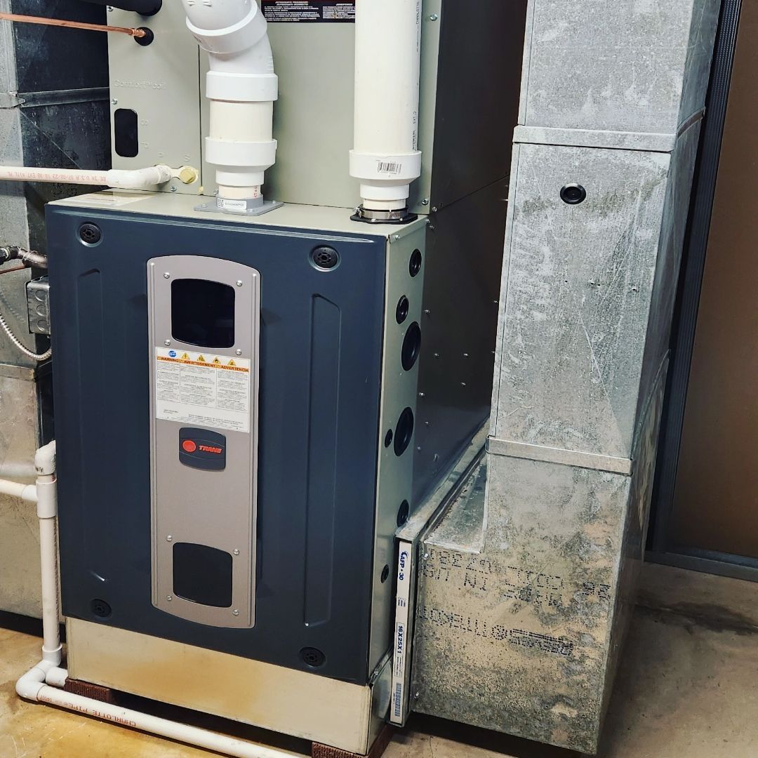 An air conditioner is sitting in a room next to a pipe