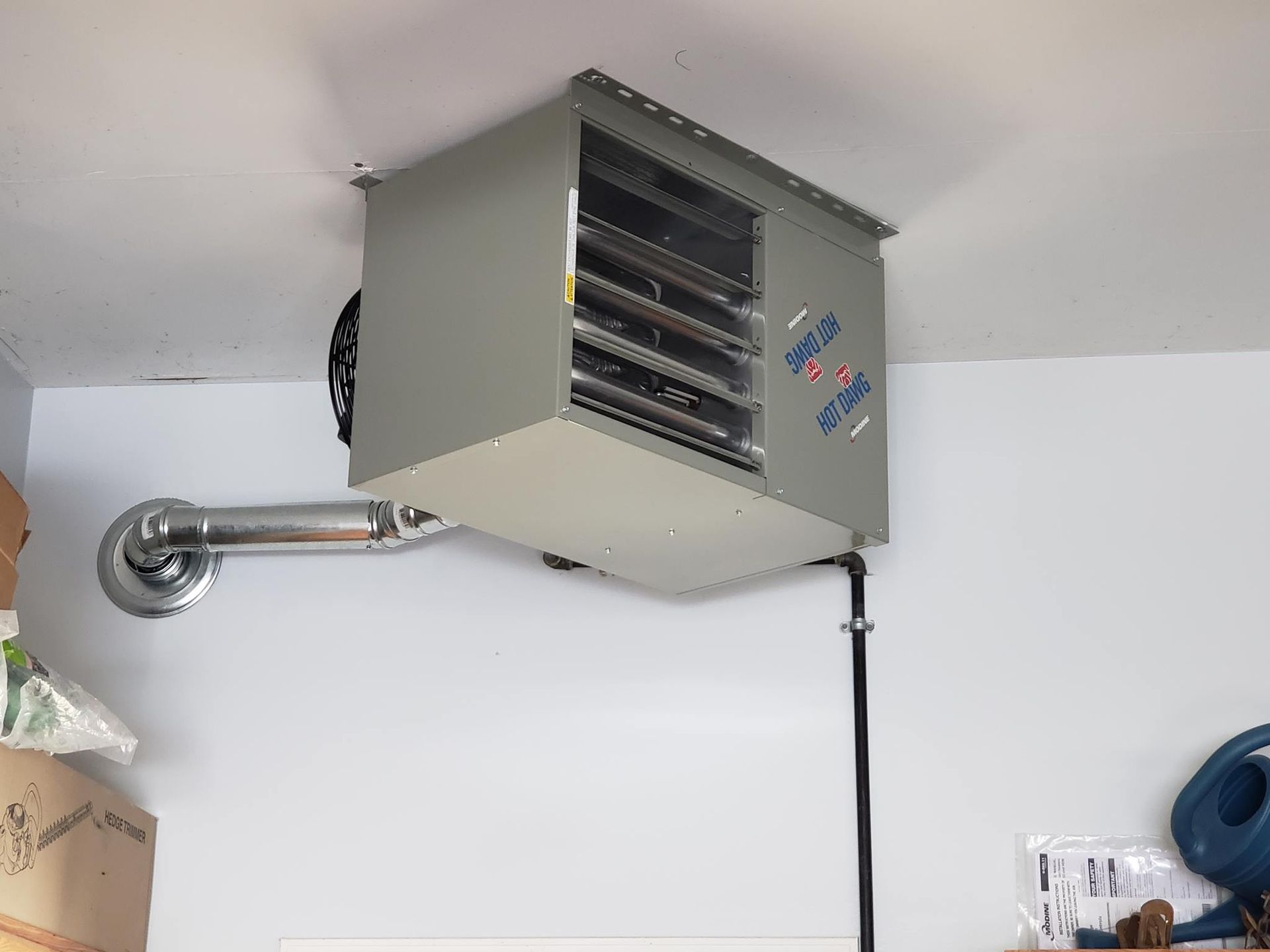 a heater is hanging from the ceiling in a garage .