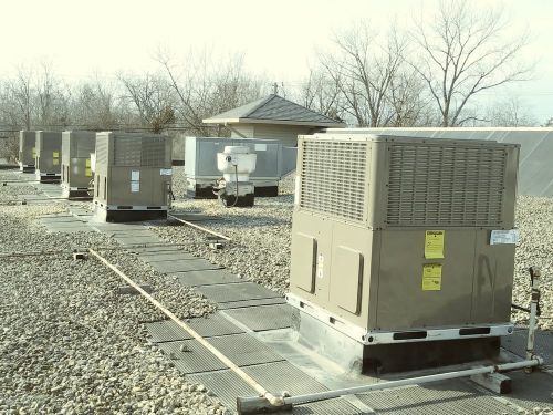 a row of air conditioners are sitting on top of a gravel covered roof .
