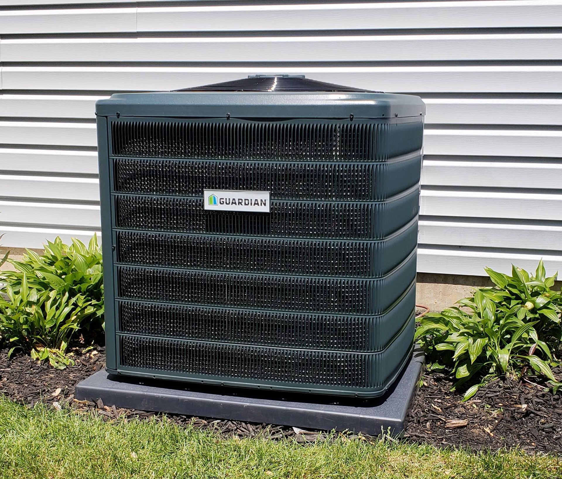 a green air conditioner is sitting in the grass in front of a building .