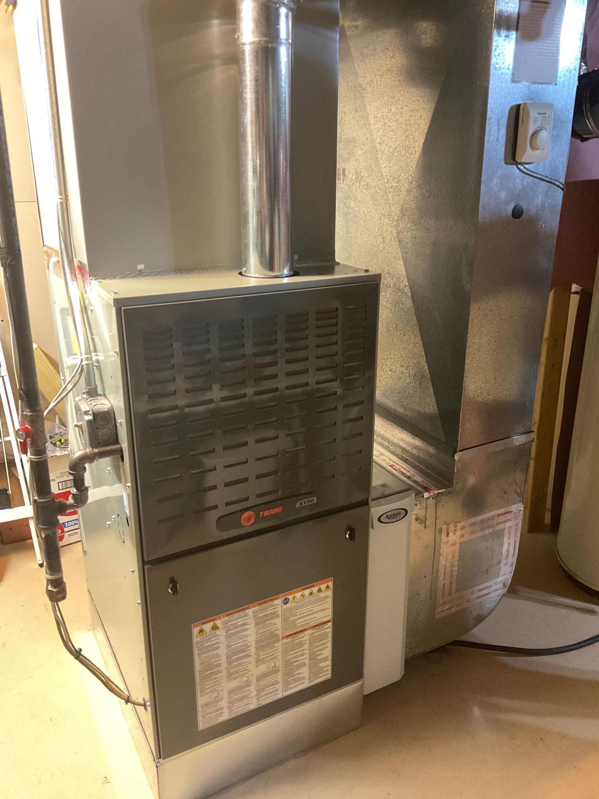 A stainless steel air conditioner is sitting on top of a wooden floor in a room.