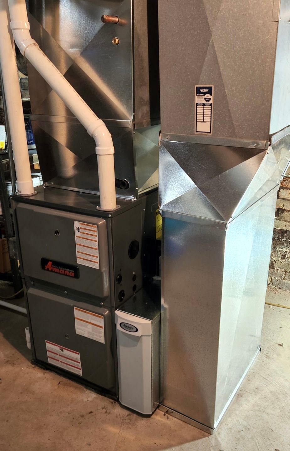 A stainless steel air conditioner is sitting in a basement.
