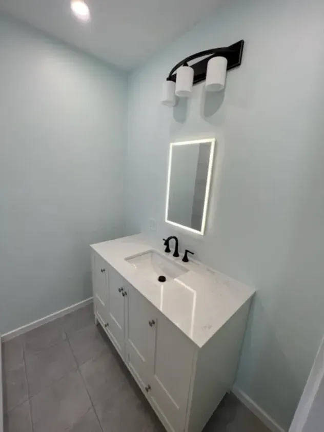 A bathroom with a sink, mirror and light fixture