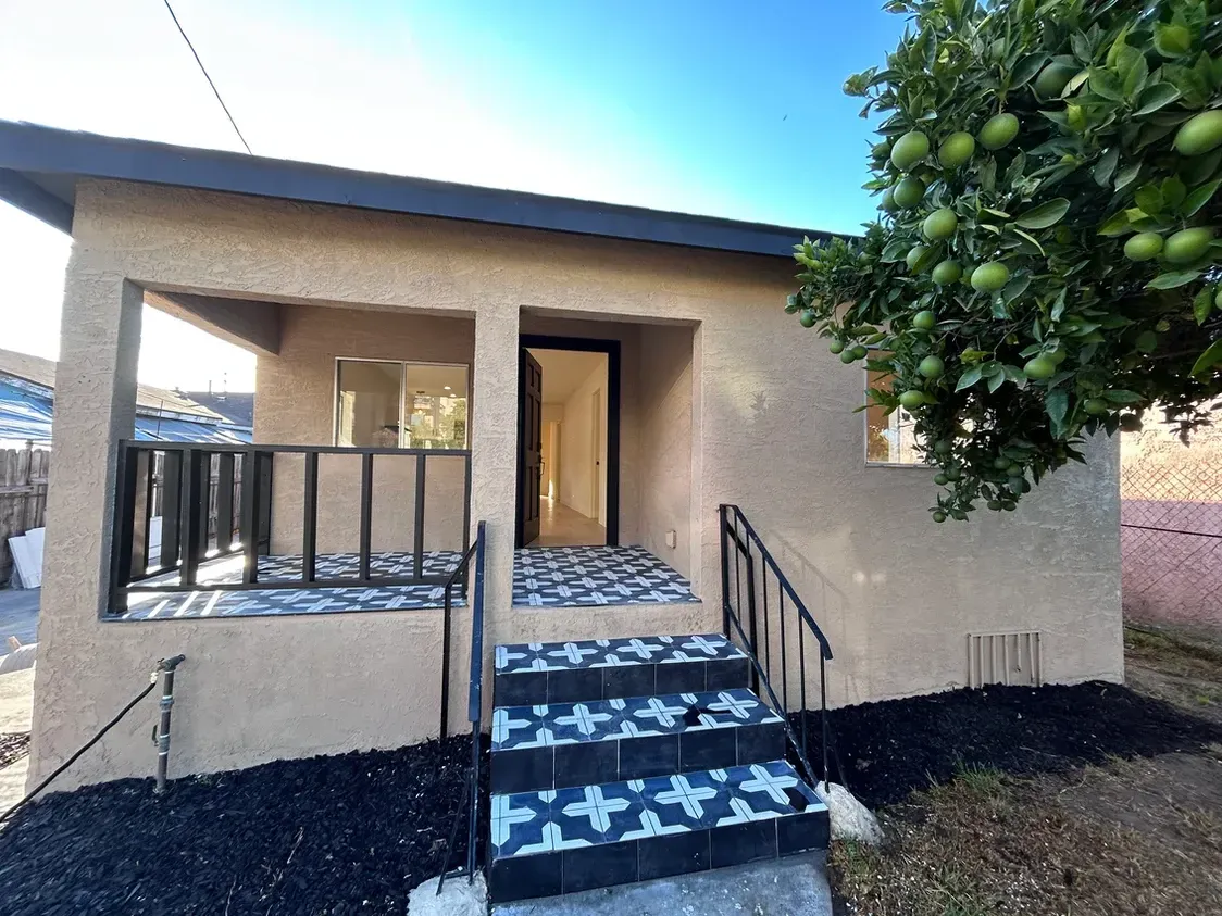 A small house with stairs leading up to it and a tree in the background.