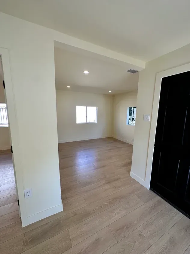 An empty room with hardwood floors and white walls.