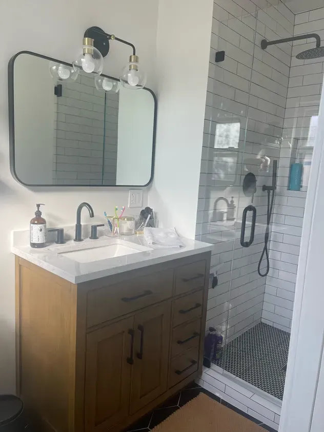 A bathroom with a sink, mirror and shower.