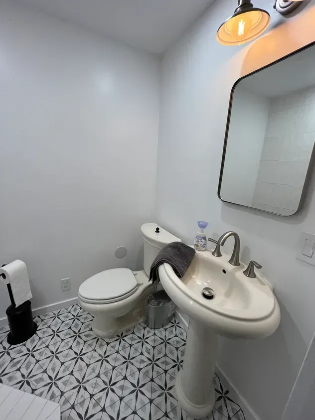 A bathroom with a toilet, sink and mirror.