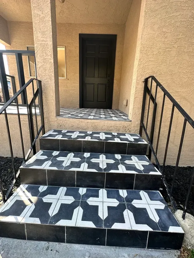 A set of black and white tiled stairs leading up to a door.