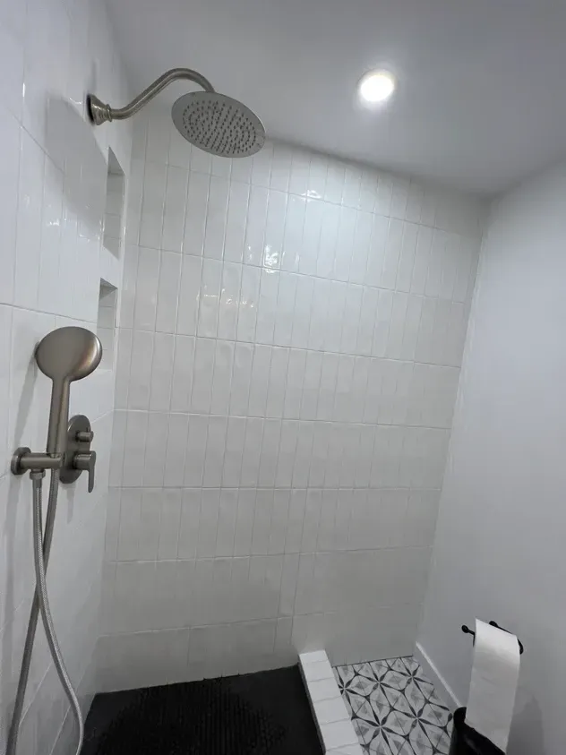 A bathroom with a shower head and a towel rack.