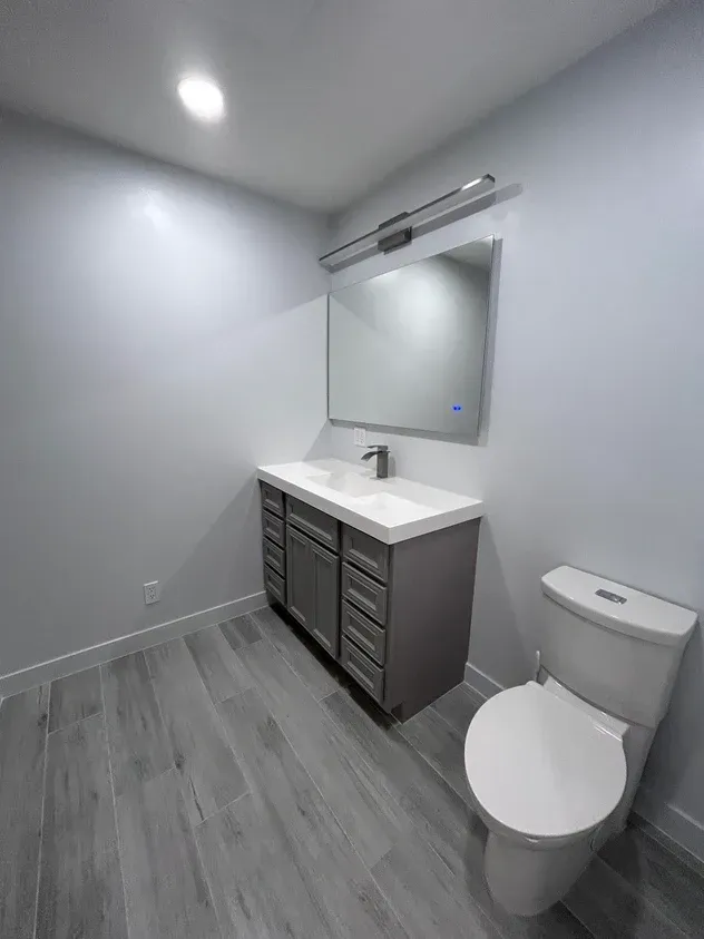 A bathroom with a sink, toilet and mirror.