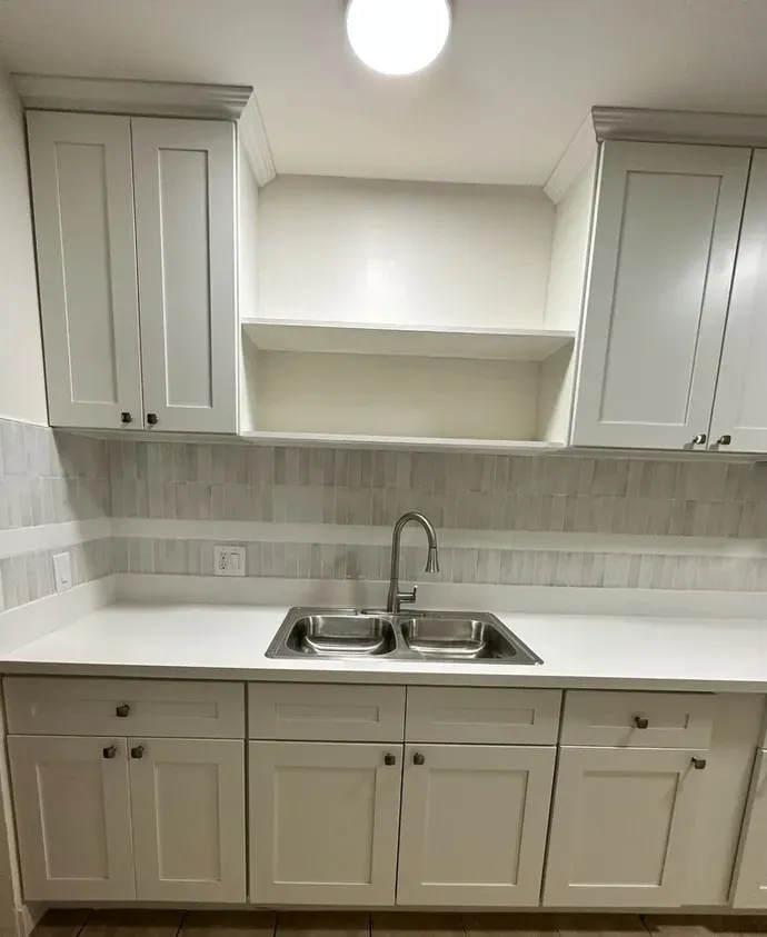 A kitchen with white cabinets and a sink.