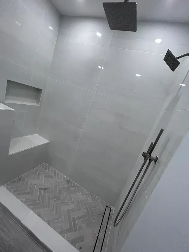 A shower with a glass door and a shower head.