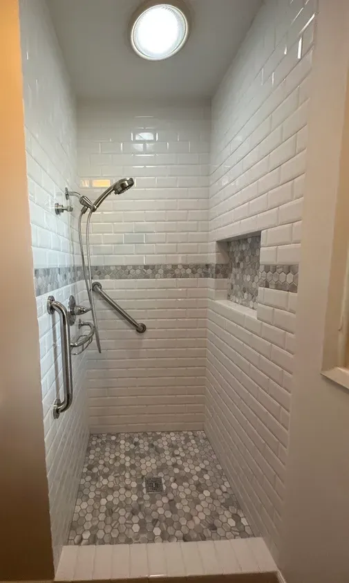A bathroom with a walk in shower and a skylight.
