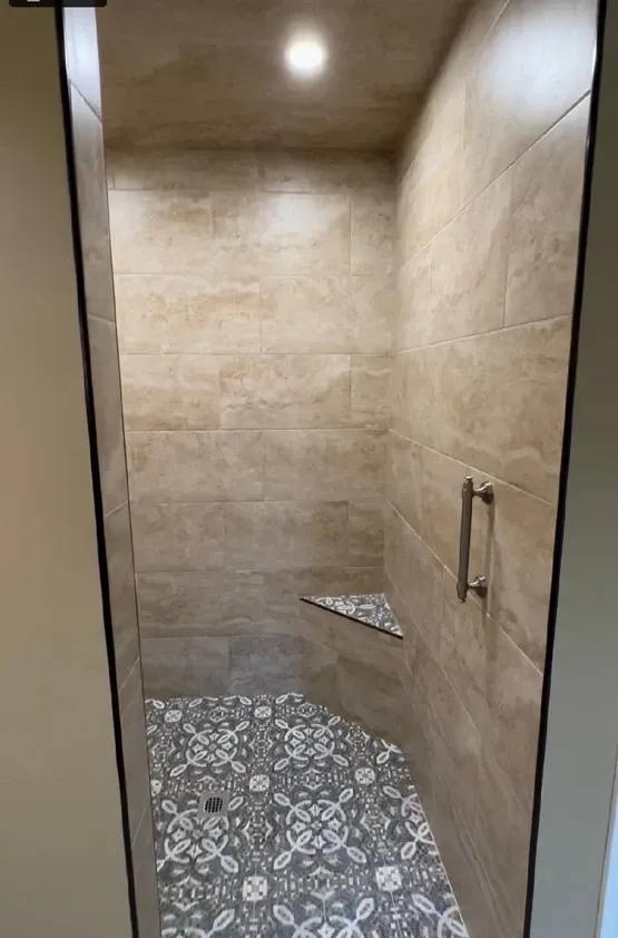 A bathroom with a walk in shower and a floral tile floor.