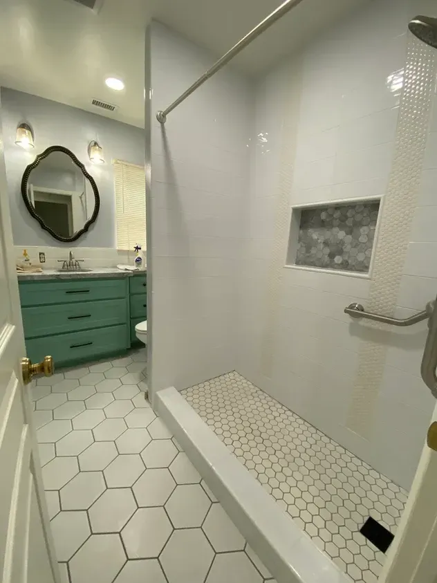 A bathroom with a walk in shower, sink, mirror and toilet.