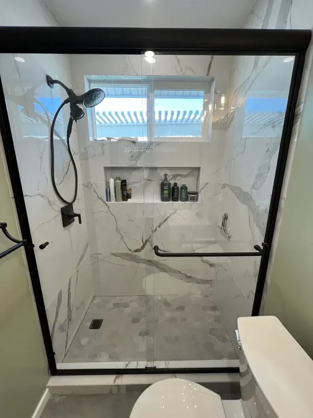 A bathroom with a shower, toilet and window.