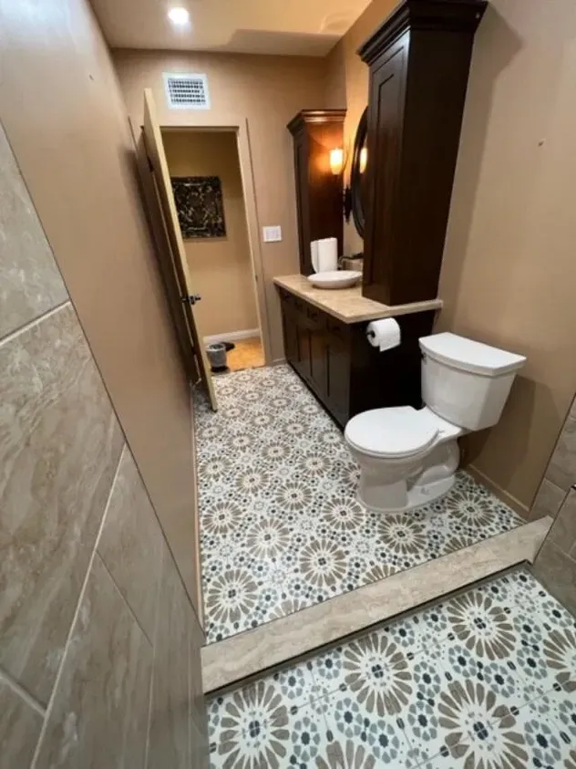 A bathroom with a toilet, sink and mirror.
