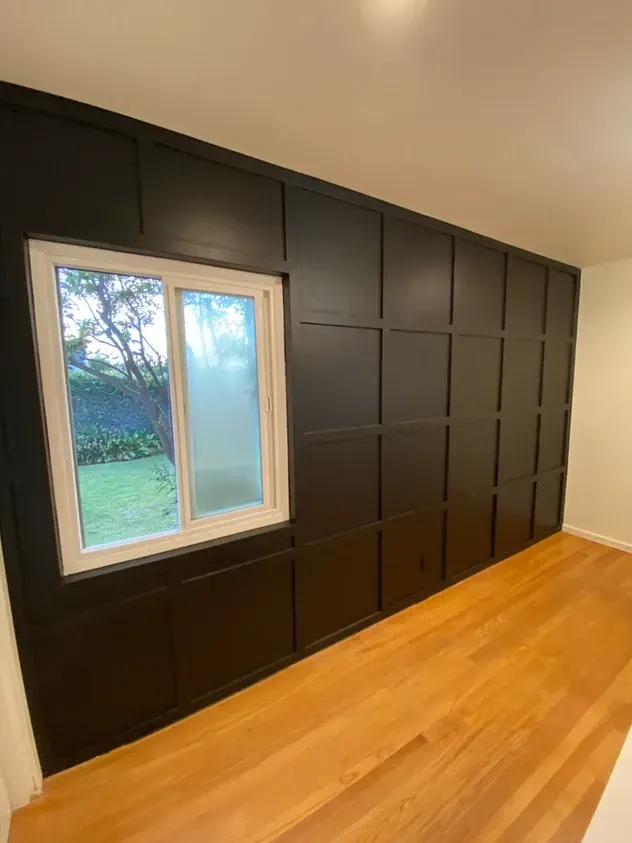 A room with a black wall and a window.