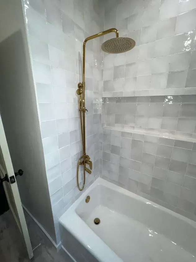 A bathroom with a bathtub and a shower head.