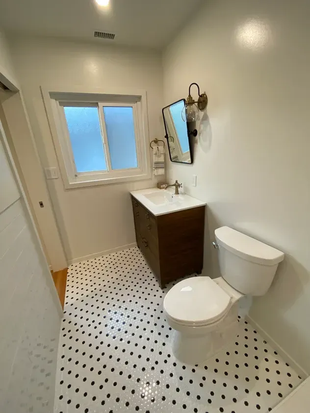 A bathroom with a toilet, sink and mirror.