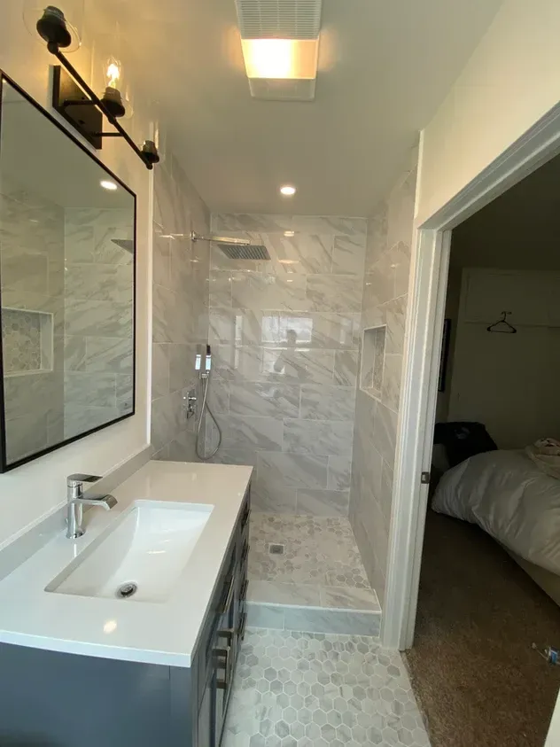 A bathroom with a sink, mirror and walk in shower.
