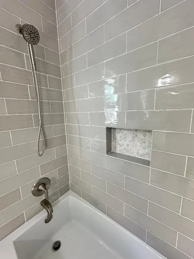 There is a bathtub in the shower with a shower head.
