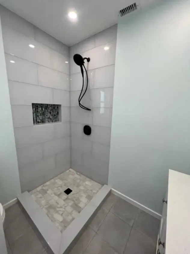 A bathroom with a walk in shower and a black shower head.
