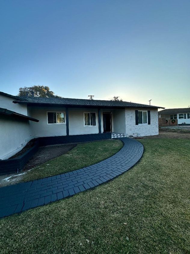 A white house with a brick walkway leading to it.