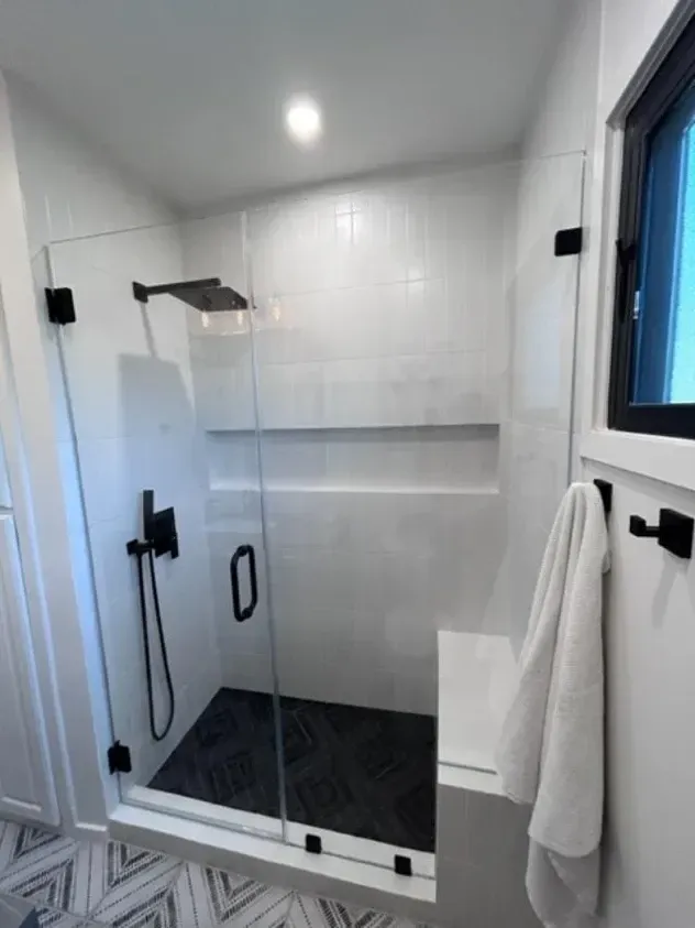 A bathroom with a walk in shower with a glass door.