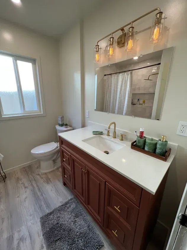 A bathroom with a sink, toilet, and mirror.