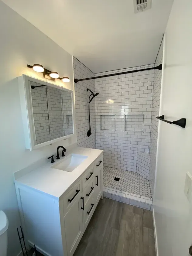 A bathroom with a sink , mirror , and shower.