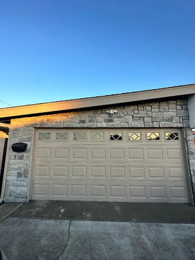 A garage door with a brick wall and a blue sky in the background.