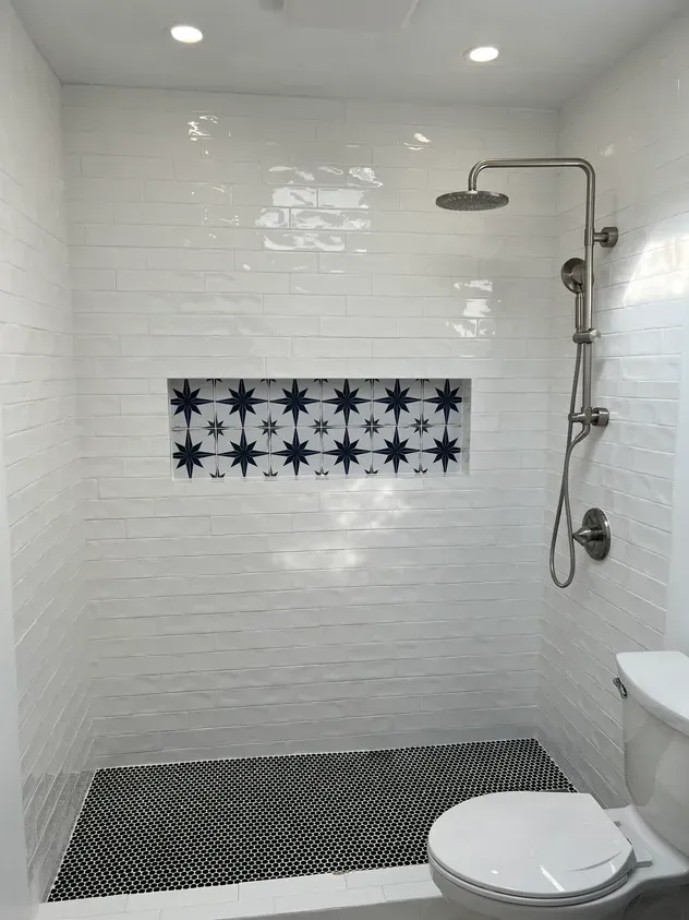 A bathroom with a toilet, shower, and black and white tiles.
