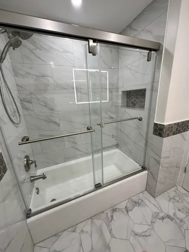 A bathroom with a bathtub and a shower with sliding glass doors.