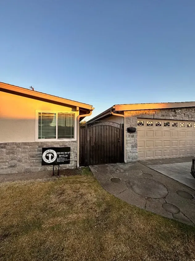 A house with a garage door and a sign in front of it.