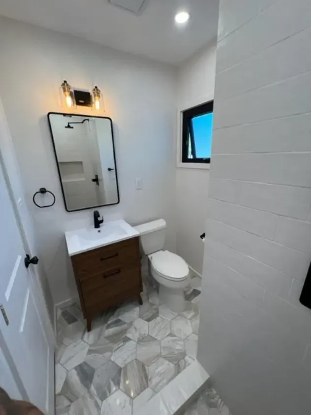 A bathroom with a toilet, sink and mirror.