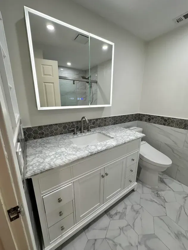 A bathroom with a sink, toilet, and mirror.