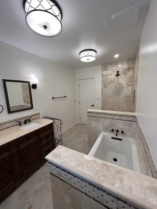 A bathroom with a tub , sink , mirror and shower.