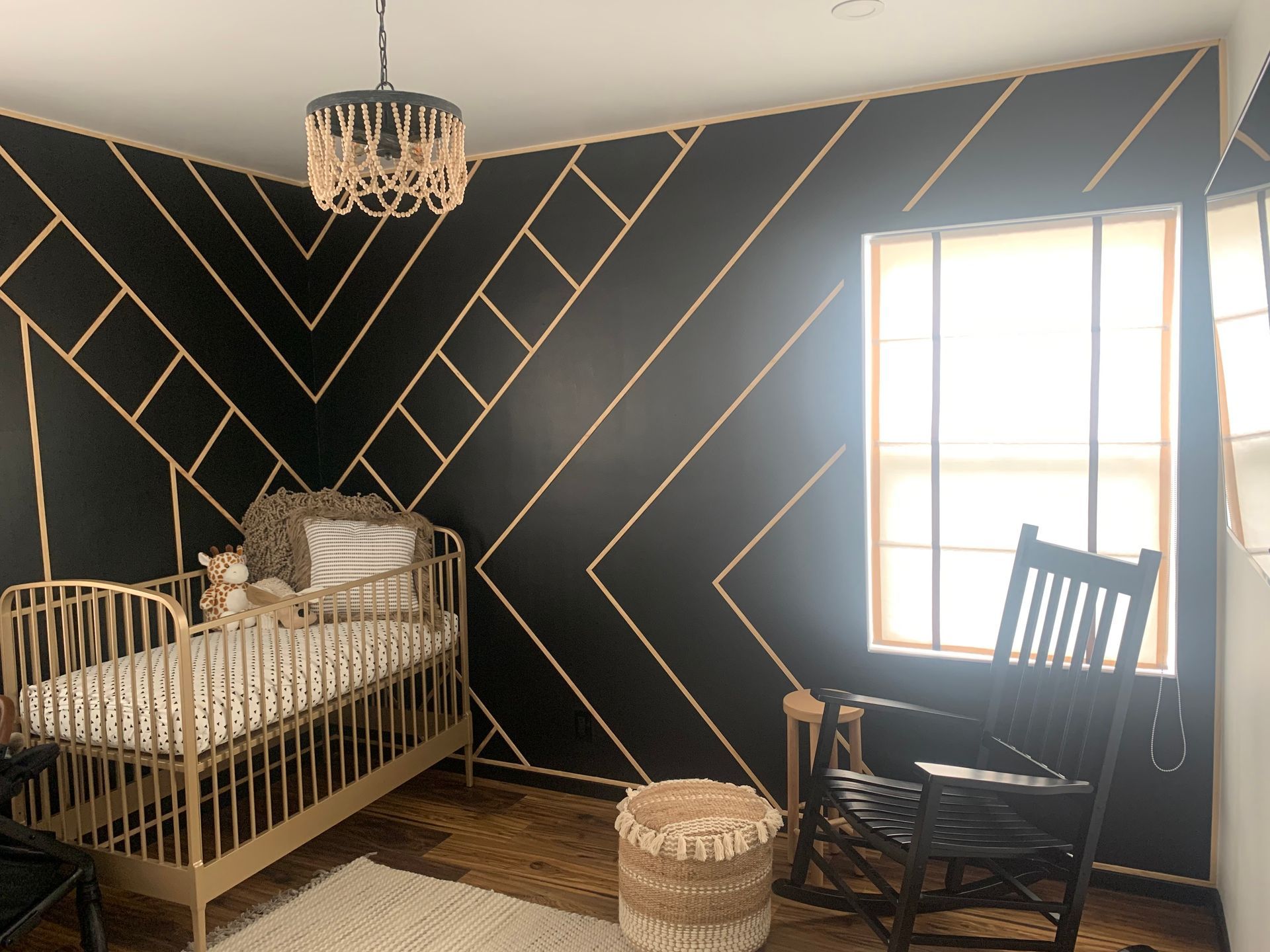 A nursery with a crib , rocking chair , and window.