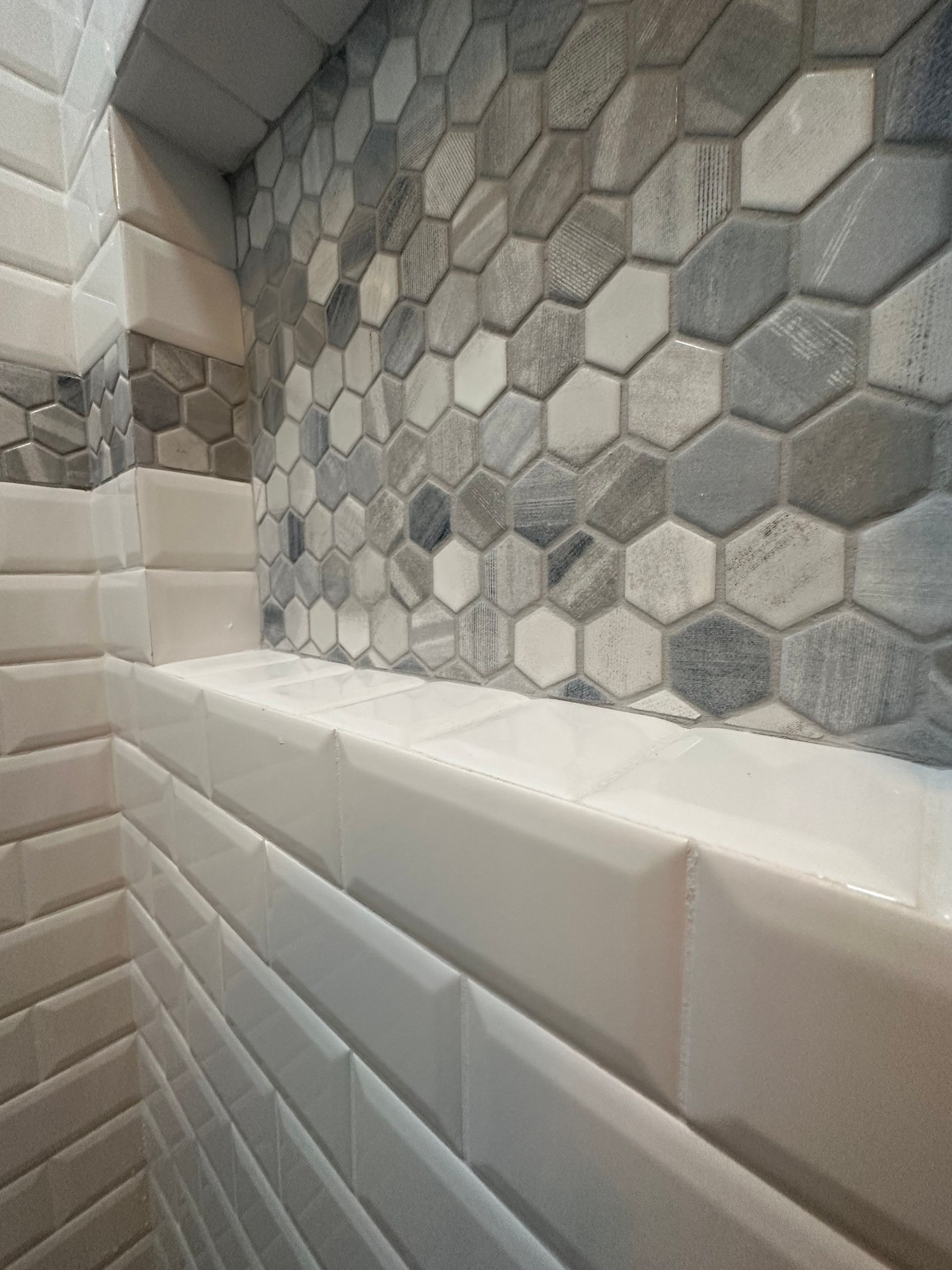 A close up of a bathroom wall with hexagonal tiles and a shelf.