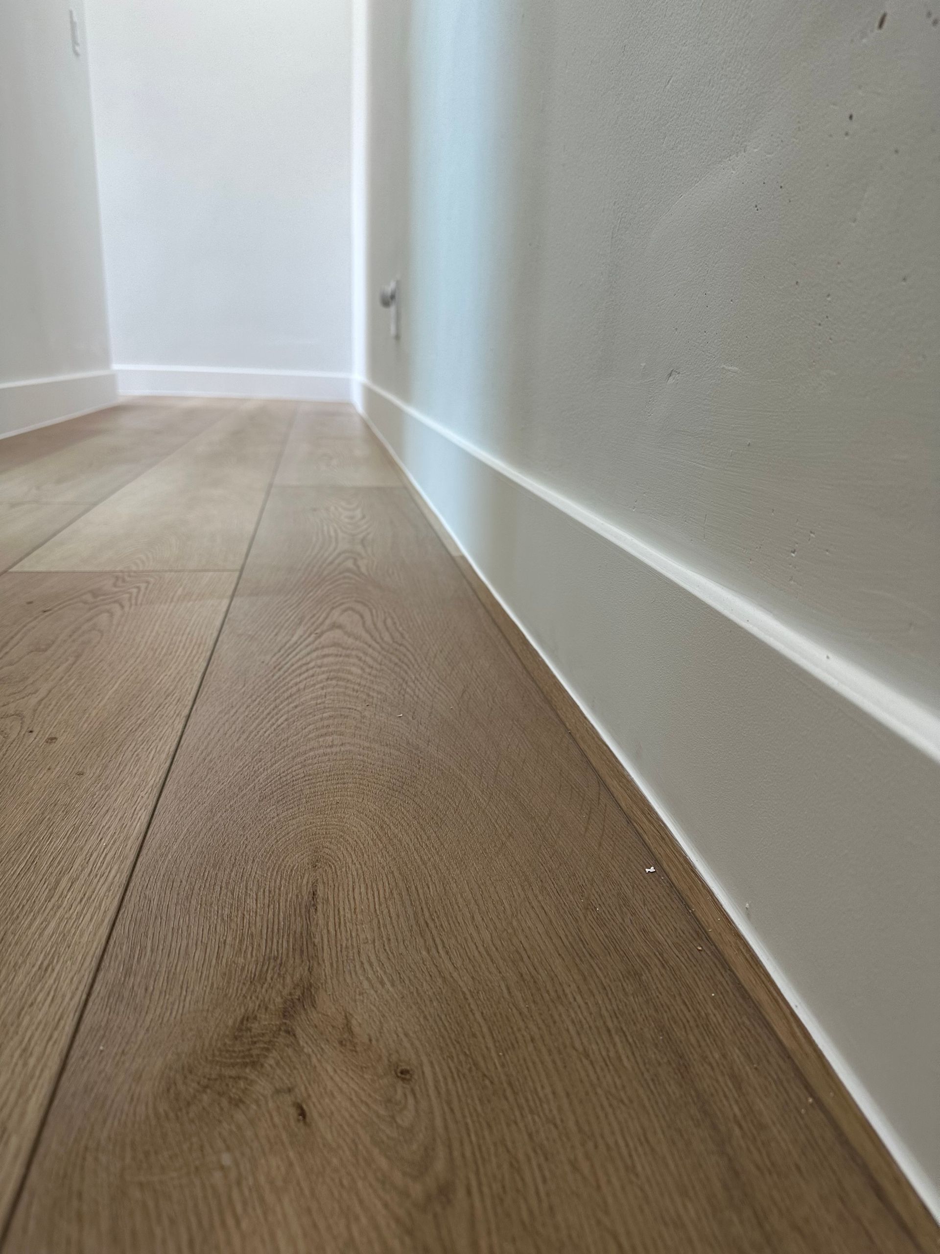 A hallway with a wooden floor and white walls.