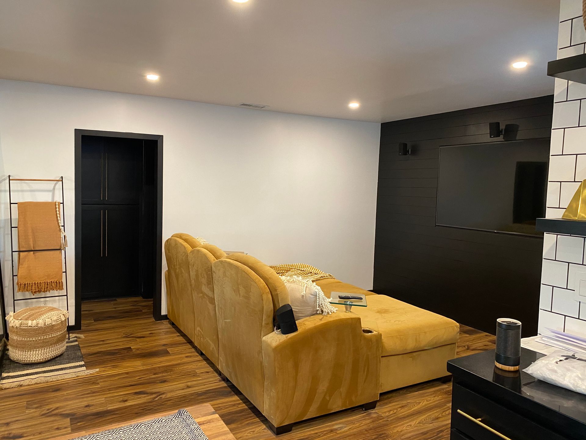A living room with a yellow couch and a flat screen tv.