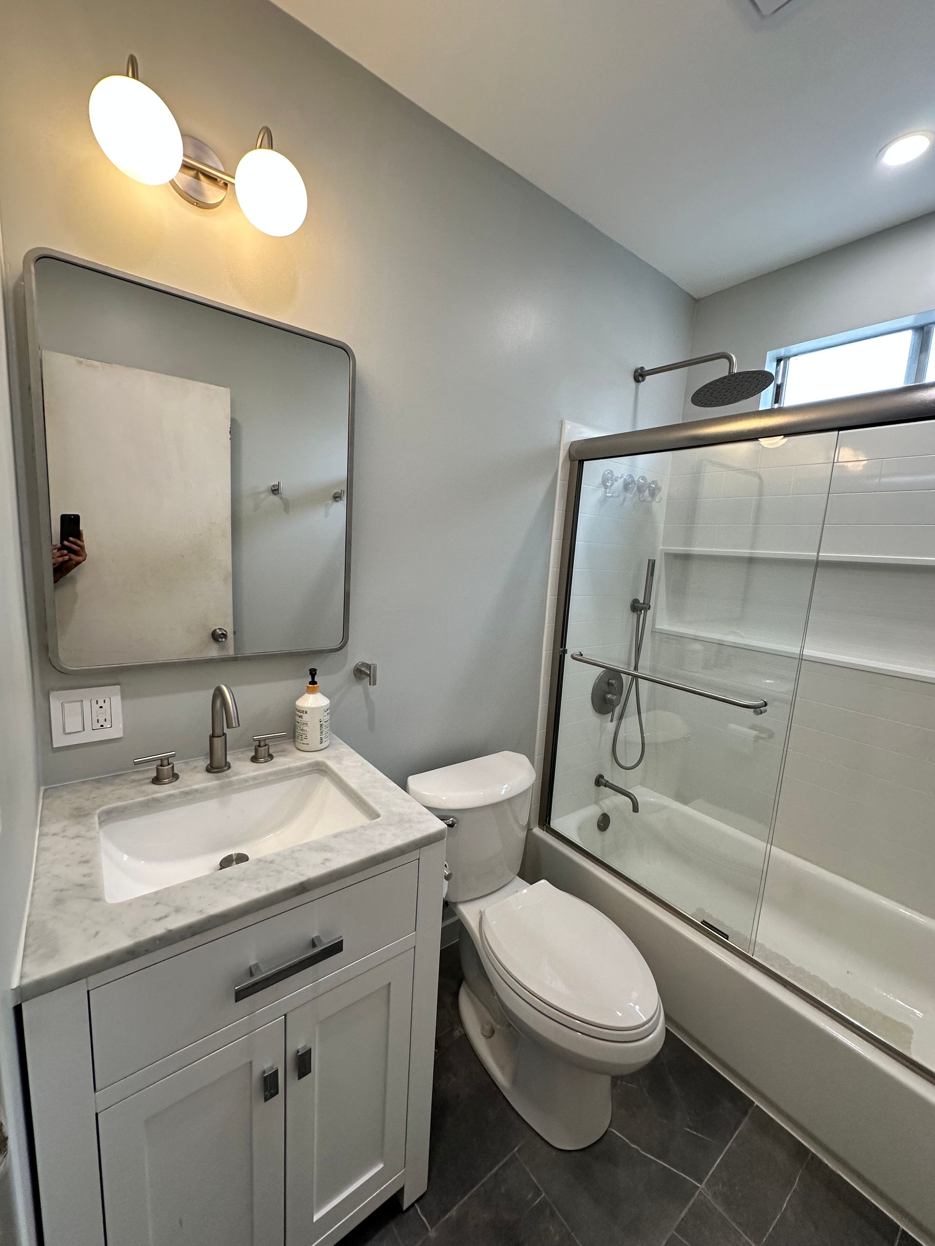 A bathroom with a toilet , sink , mirror and bathtub.