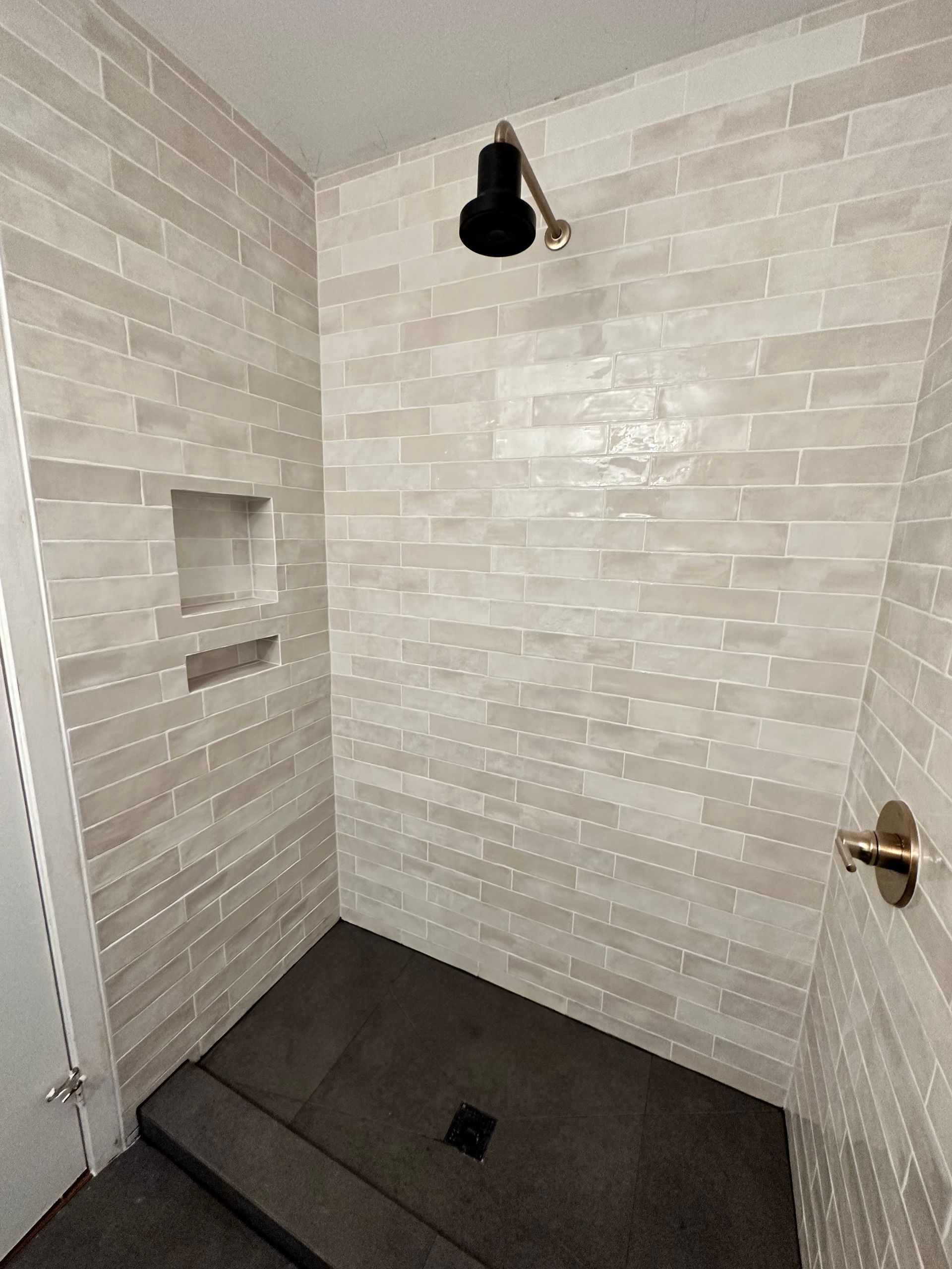 A bathroom with a walk in shower and a brick wall.