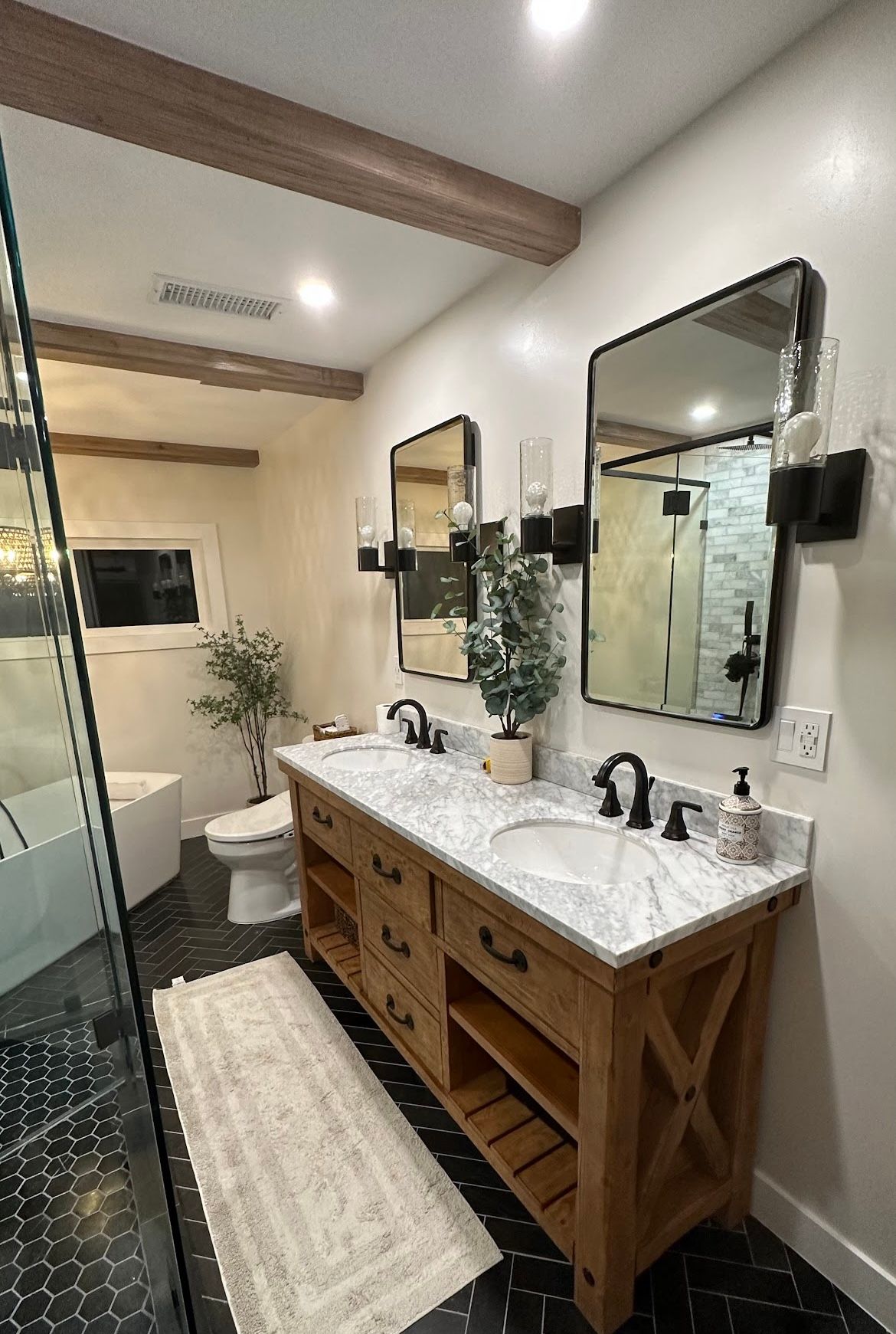A bathroom with two sinks , a toilet , and two mirrors.
