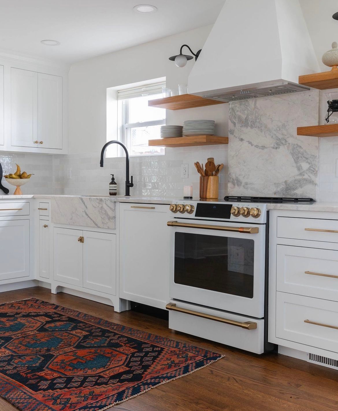A kitchen with white cabinets , a stove , a sink , and a rug.